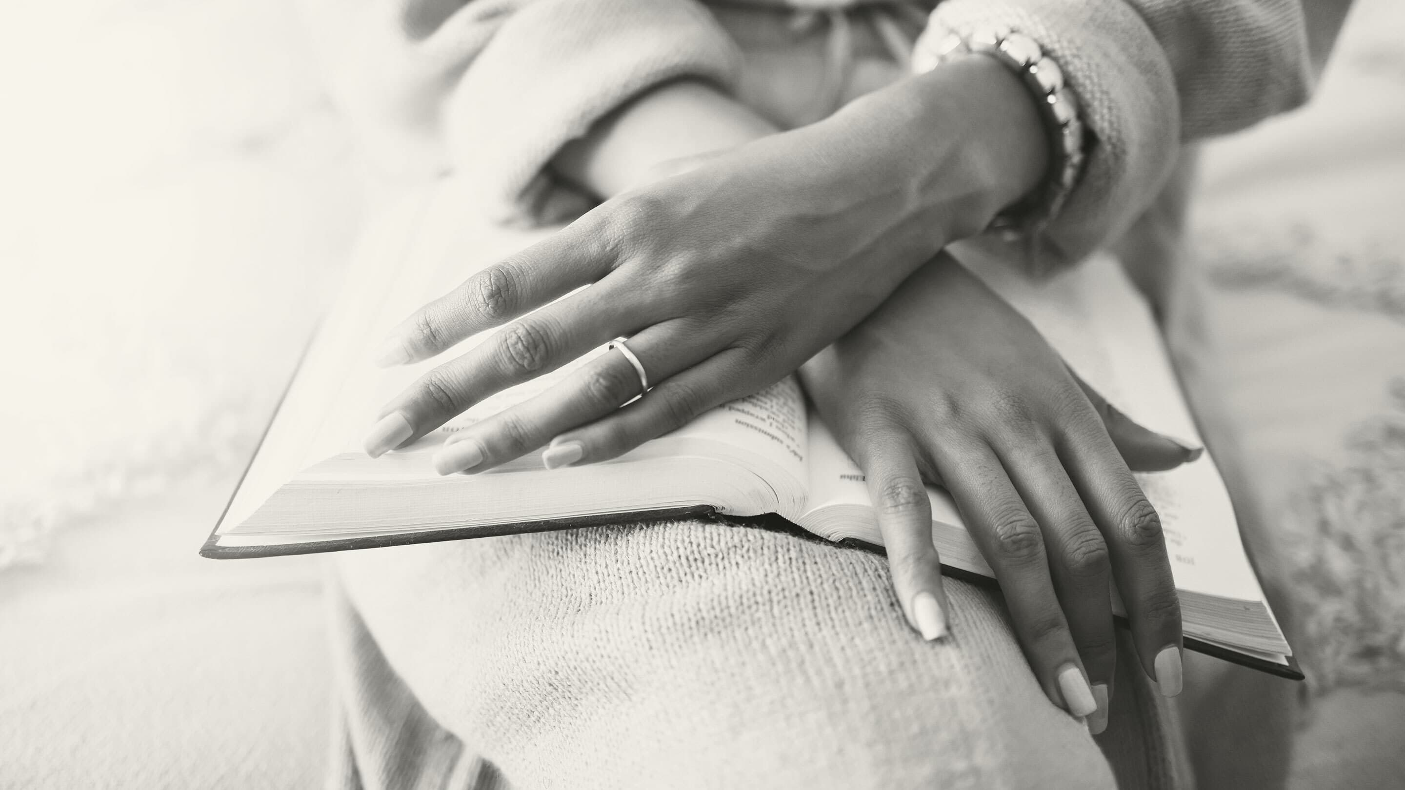 Black woman's hands folded over Bible