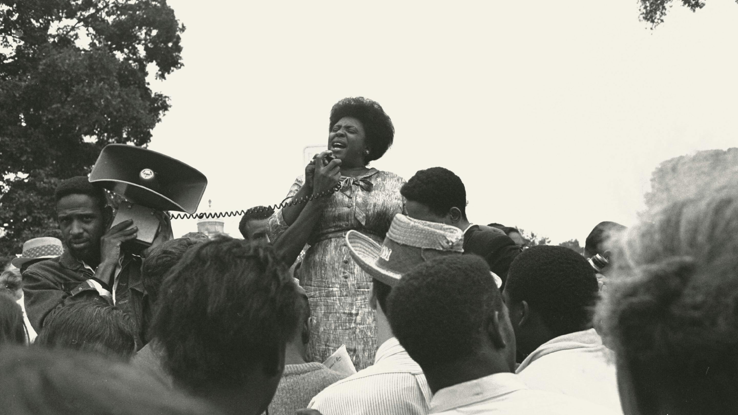Fannie Lou Hamer speaking into a microphone at an outdoor rally