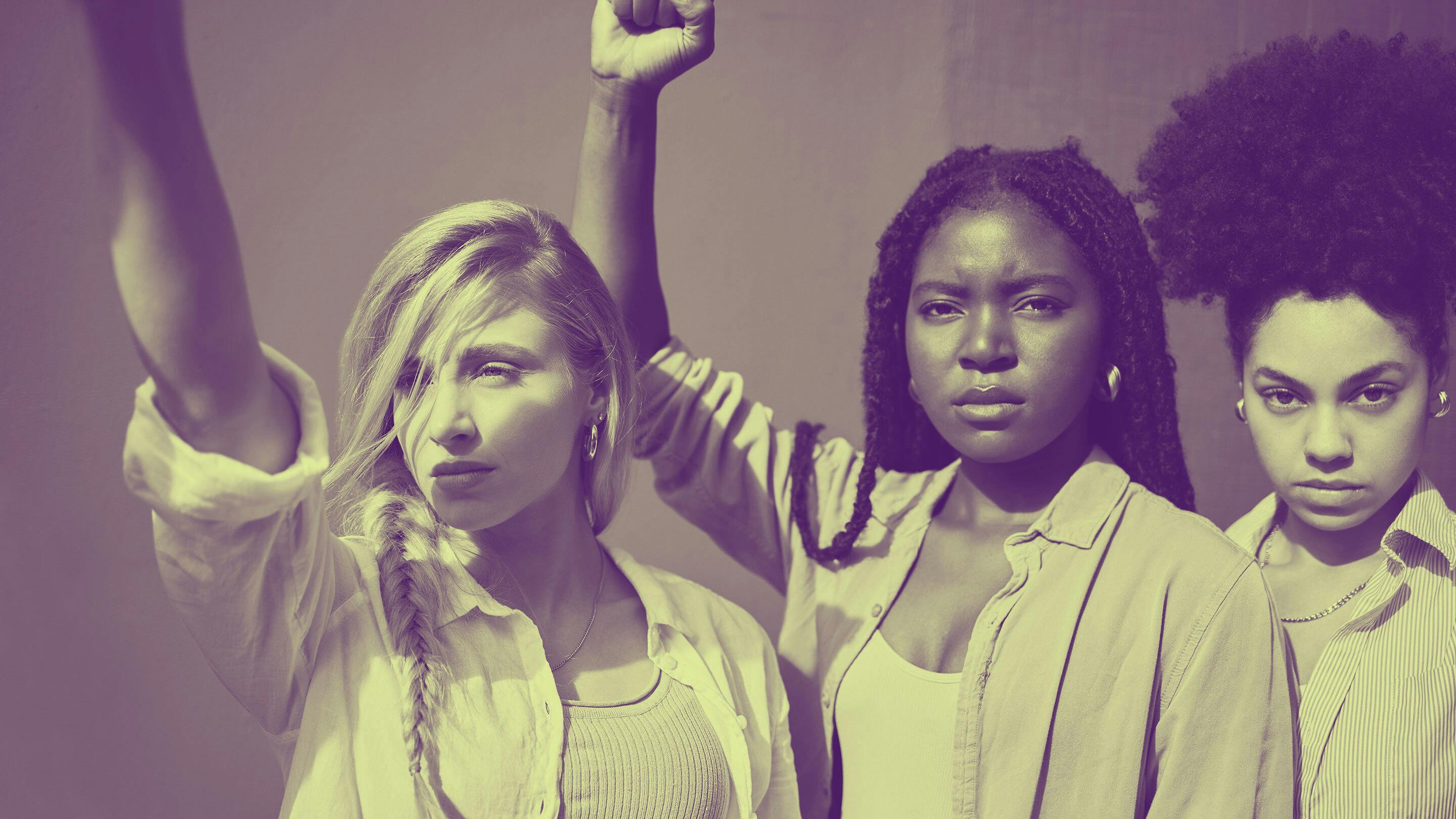 Portrait of three diverse young women with looks of defiance and fists raised